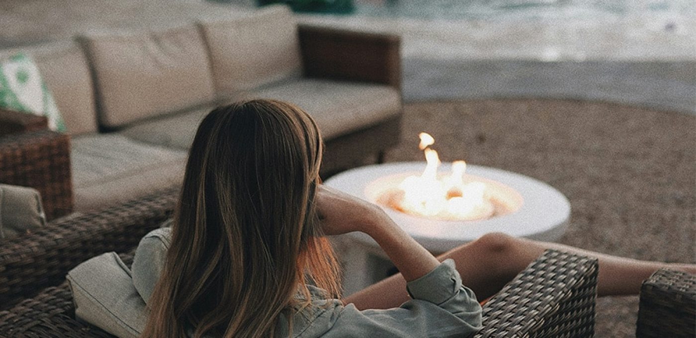 a woman sitting in a chair by a fire pit